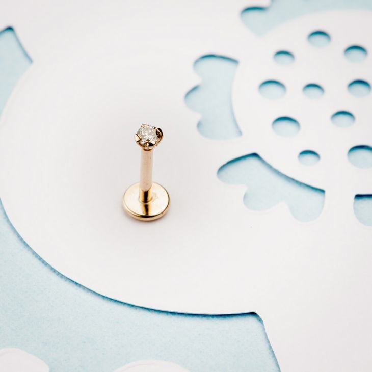 14k yellow gold 2mm diamond flat back labret stud displayed upright on decorative paper background