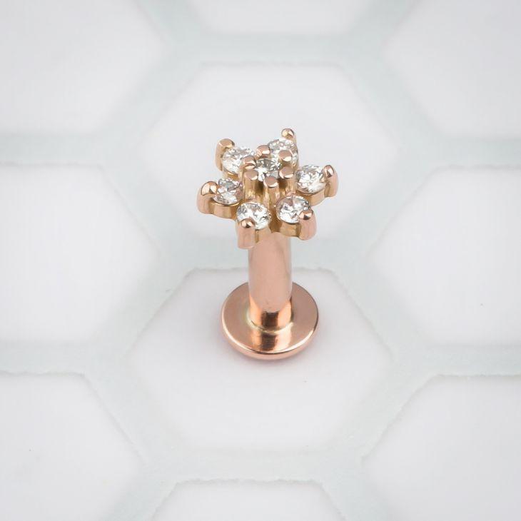 14k rose gold CZ flower flat back labret, front view showing clear CZ charm on white hexagon background
