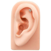 CZ flower flat back labret stud in helix position on silicone ear display, showing placement and scale