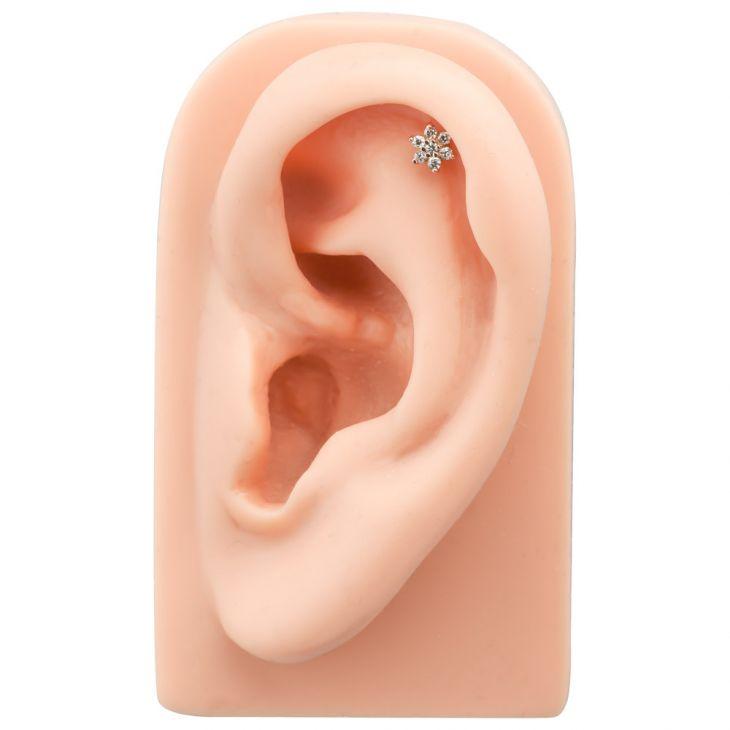 CZ flower flat back labret stud in helix position on silicone ear display, showing placement and scale