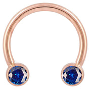 14k rose gold circular barbell with deep blue CZ bezel ends, front view showing warm pink-gold tone