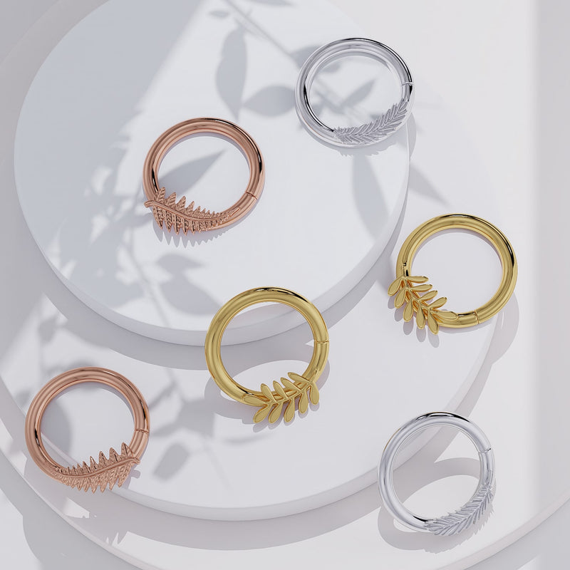 Feather seam ring hoops in 14K yellow gold, rose gold, and white gold displayed on styled surface