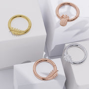 Tropical-themed 14K gold seam rings in yellow and rose gold with leaf and pineapple charms, styled on white blocks