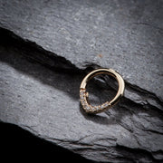 14K yellow gold CZ clicker ring resting on dark slate stone, lifestyle angle view