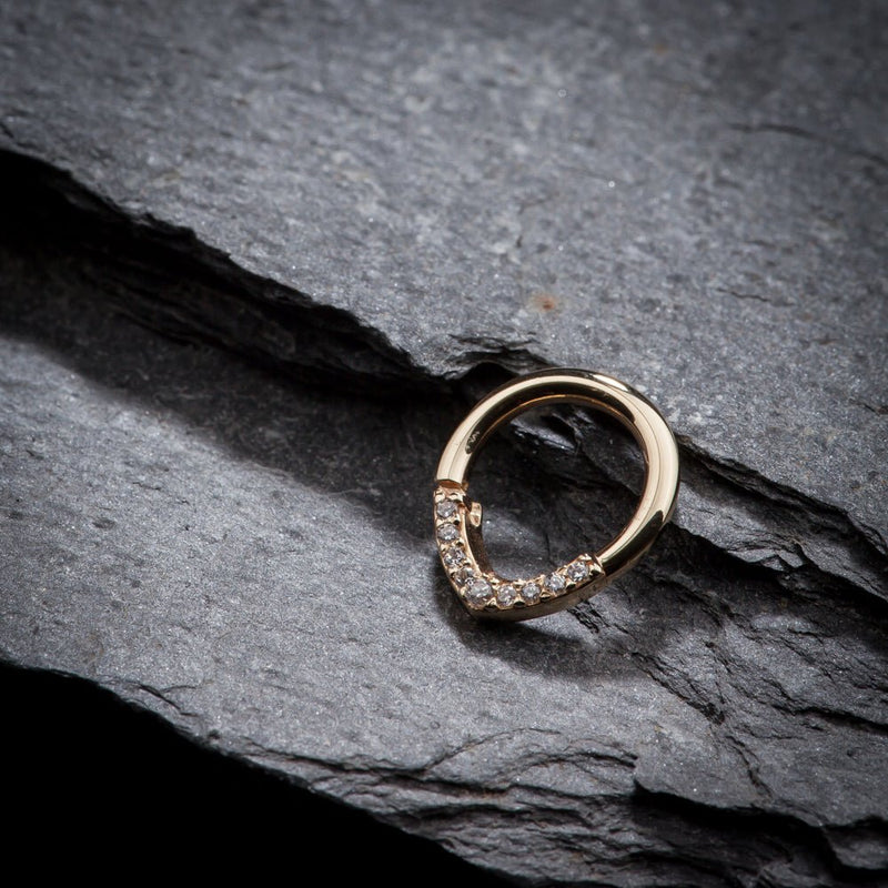 14K yellow gold CZ clicker ring resting on dark slate stone, lifestyle angle view