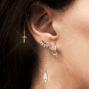 Gold dagger chain accessory shown on pierced ear alongside other earrings, styled for scale and fit