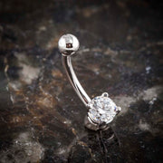 14k white gold solitaire CZ belly ring on dark stone surface, angled lifestyle shot