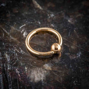 14K rose gold fixed bead ring on dark stone surface, angled view showing warm gold tone
