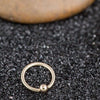 14K yellow gold fixed bead ring nestled in black gravel, lifestyle close-up showing small size
