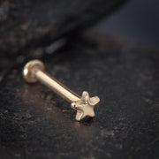 14k rose gold tiny star flat back labret stud on dark stone surface, angled side view