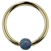 14K yellow gold captive bead ring with teal simulated opal bead, front view on white background