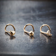 Three 14K yellow gold nose rings side by side: puffy heart, puffy star, and crescent moon styles