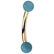 14K yellow gold curved barbell with faux turquoise ball ends, side view