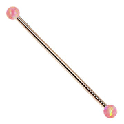 14k rose gold industrial barbell with pink synthetic opal ball ends, front view on white background