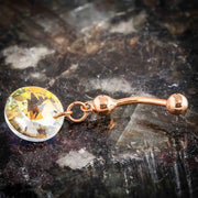 14k rose gold Swarovski rivoli belly ring laid flat on dark stone surface, angled lifestyle shot