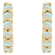 Close-up front view of 14k yellow gold huggie hoops showing paired opal stone detail and prong setting