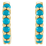 Close-up front view of paired 14k yellow gold huggie hoops showing turquoise cabochon stone detail