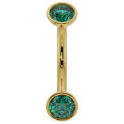14k yellow gold 14G curved barbell with larger bezel-set emeralds, showing fuller stone size