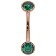 14k rose gold 14G curved barbell with larger bezel-set emeralds, warm pink tone contrast