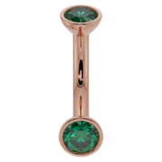 14k rose gold 14G emerald bezel curved barbell, angled view highlighting warm tone and green stones