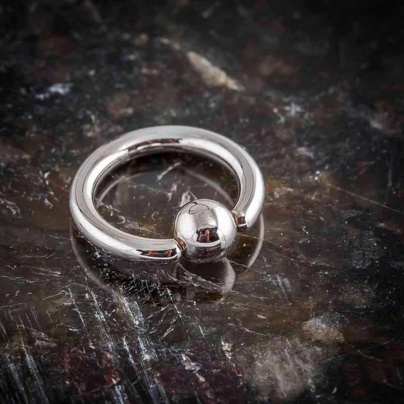 14K white gold fixed bead ring on dark marble surface, angled view highlighting bead closure