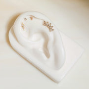 14k gold white sapphire crescent stud displayed in upper lobe position on white ceramic ear model