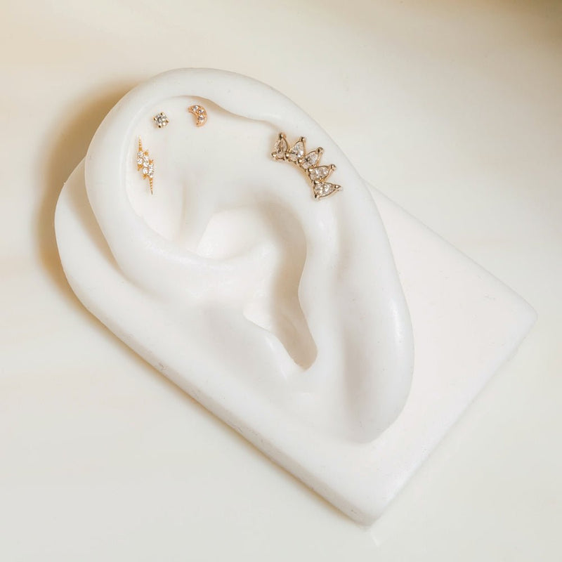 14k gold white sapphire crescent stud displayed in upper lobe position on white ceramic ear model