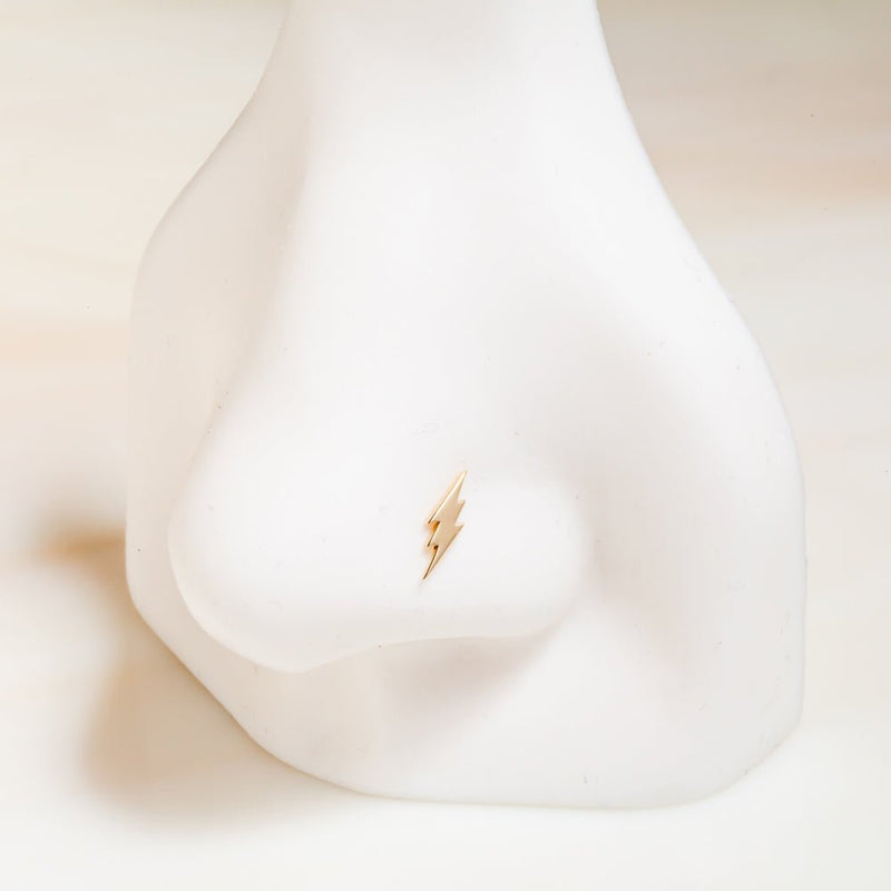 14k yellow gold lightning bolt flat back stud shown on nose mannequin, demonstrating petite fit in nostril