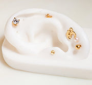 14k gold yin yang flat back stud displayed on white ear mannequin alongside other dainty gold studs