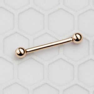 14k rose gold straight barbell laid flat on hexagon tile surface showing full length and ball ends