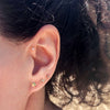 Gold star stud earring on model's lobe in a curated ear stack with lightning bolt and moon studs