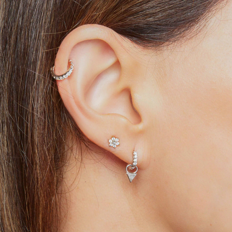 14k white gold CZ clicker hoop shown in helix and lobe piercings with silver flower stud on model