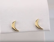 Pair of 14k yellow gold crescent moon studs displayed on white jewelry cushion, front-facing view