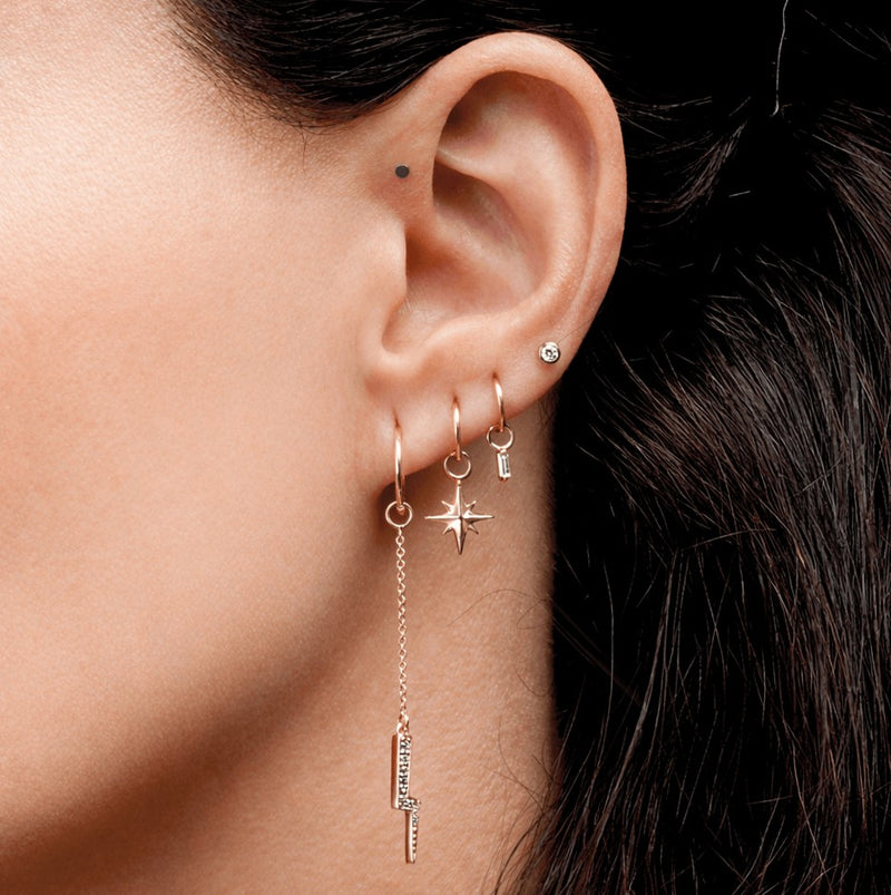 Diamond bezel stud in upper lobe piercing styled with rose gold charm hoops, ear stack lifestyle shot