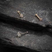 14k gold CZ nose bone and pin-post styles in yellow, white, and rose gold on slate stone surface