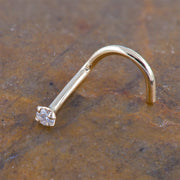 14k yellow gold CZ nose ring twist style resting on stone surface, showing warm gold tone