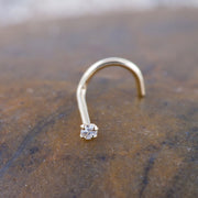 14k yellow gold CZ twist nose ring on stone surface, angled view showing screw backing shape