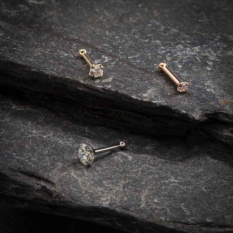 Yellow, white, and rose gold 3mm CZ nose bone and pin post styles arranged on slate background
