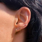 Gold box chain piercing connector on model's ear shown with hoop and gold moon stud styling
