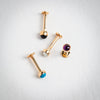 14k yellow gold flat back labrets with black onyx, pearl, turquoise, and amethyst tops, overhead view
