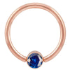 14k rose gold blue CZ bezel fixed bead ring, angled view highlighting the deep blue stone and setting