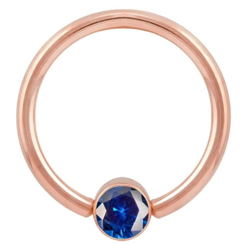 14k rose gold blue CZ bezel fixed bead ring, angled view highlighting the deep blue stone and setting