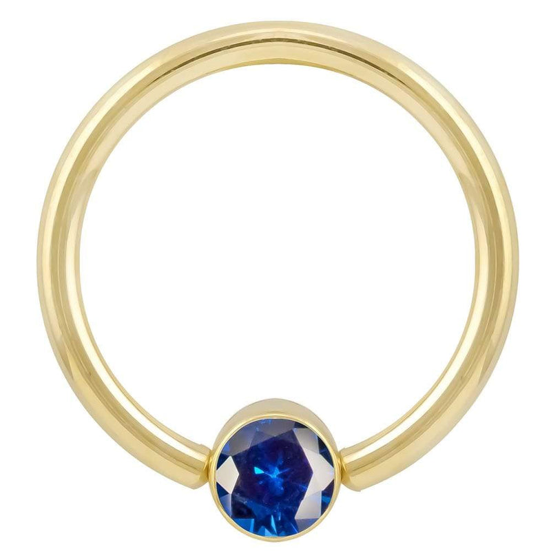 14k yellow gold fixed bead ring with blue CZ bezel, angled front view showing stone detail