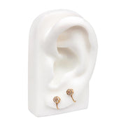 Yellow gold box chain connector on white ear display linking two CZ flower studs in lobe piercings