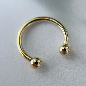 Close-up of 14k yellow gold horseshoe barbell showing mirror-polished finish and threaded ball ends