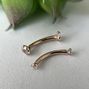 Two 14k rose gold diamond curved barbells laid flat, showing size comparison of different lengths