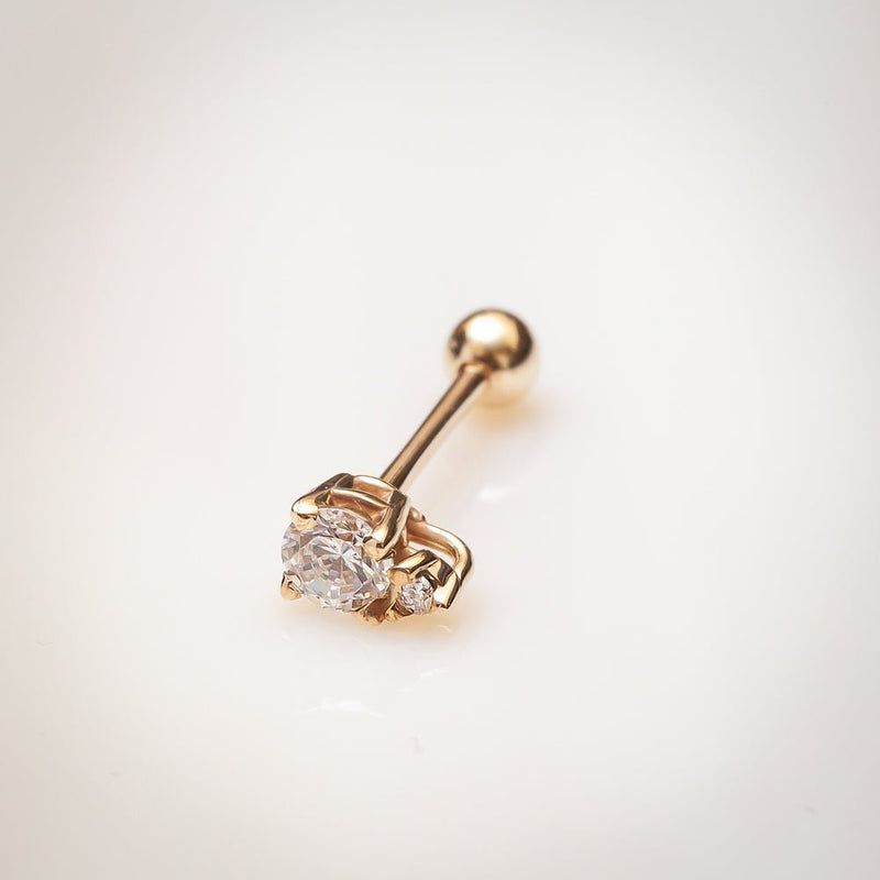 14k yellow gold birthstone cartilage stud with CZ, lifestyle shot on warm surface