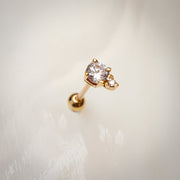 14k yellow gold CZ cartilage stud earring resting on soft white textured surface