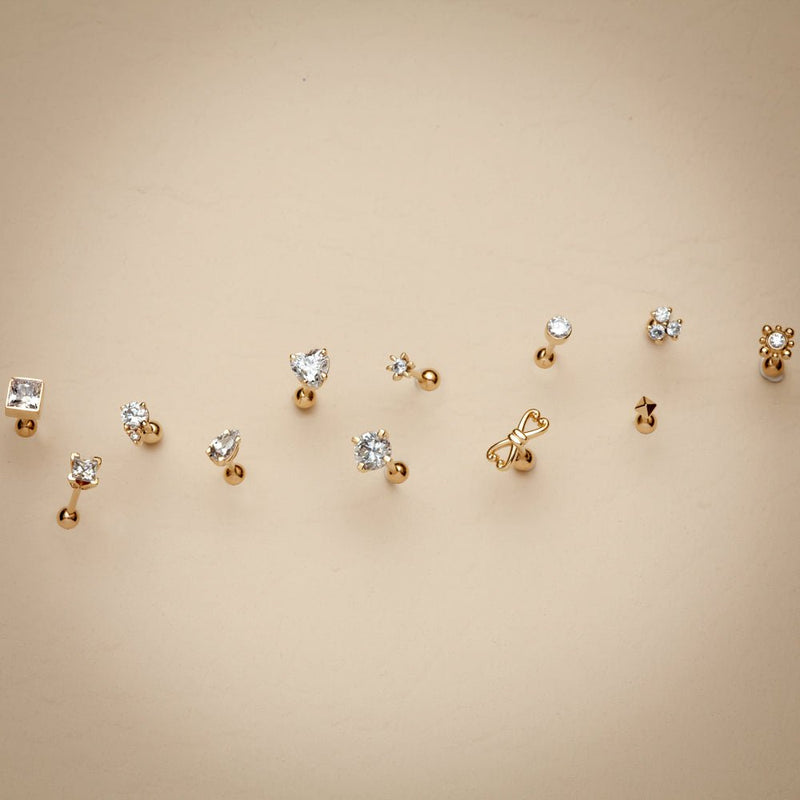 Assorted 14k gold cartilage stud earring styles laid out flat showing variety of designs
