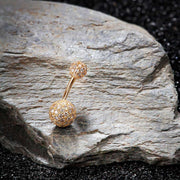 14k yellow gold diamond pave navel ring resting on natural stone, lifestyle scale shot